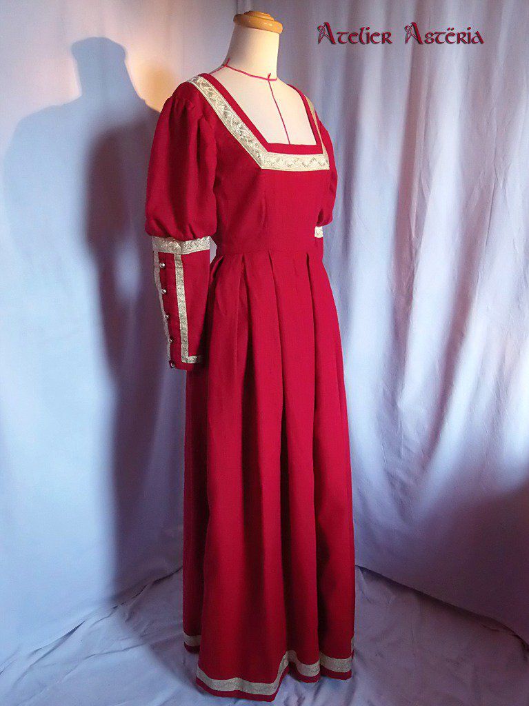 Robe fantasy en lin rouge et galons dorés, encolure carré, jupe à plis ronds et deux très grandes poches cachées dans les coutures côtés, manches fantaisie et laçage dans le dos - Fantasy dress in red linen and gold braid